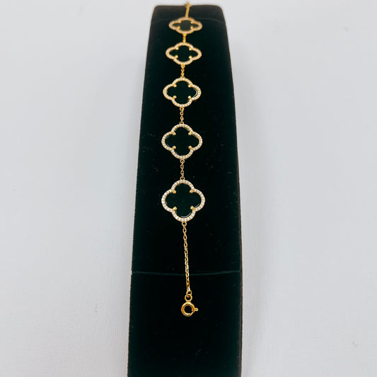Guld armband med svarta klöver stenar